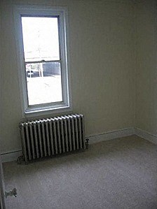 an empty room with a radiator and a window