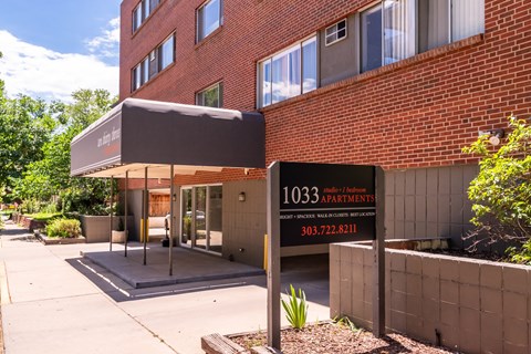The image shows a building with a sign that reads "1033 apartments" and a phone number.