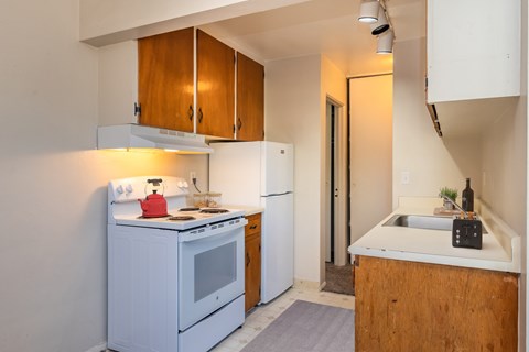 A small kitchen with a white oven and a white fridge.