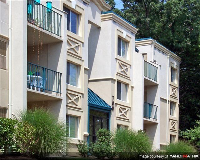 a white apartment building with balconies and trees