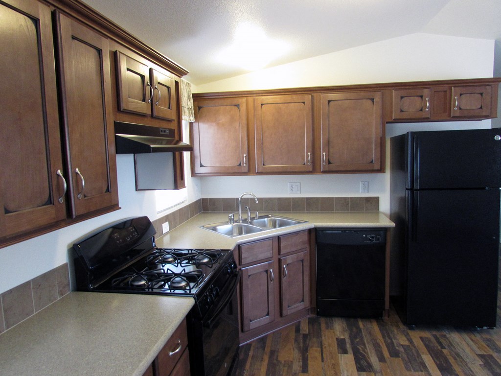 an empty kitchen with wooden cabinets and black appliances