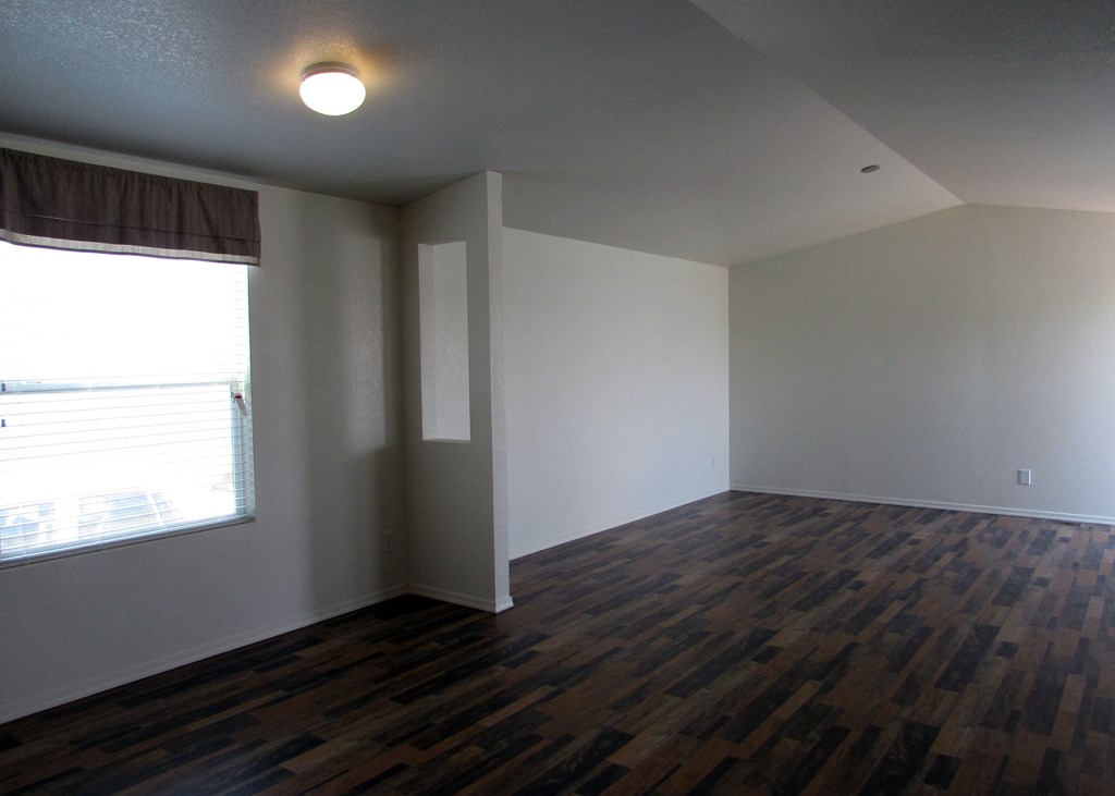 an empty living room with a large window an empty living room with a large window