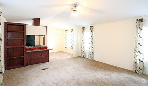 an empty living room with a cabinet and a ceiling fan
