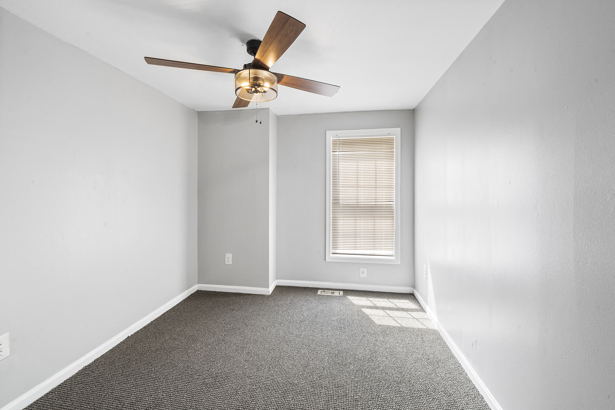 an empty room with a ceiling fan and a window