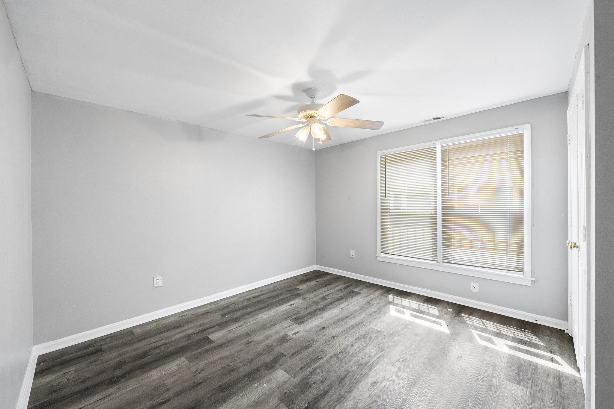 an empty bedroom with a ceiling fan and a window
