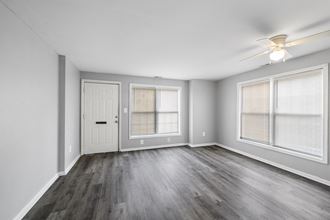 the living room of an empty apartment with wood flooring and a ceiling fan