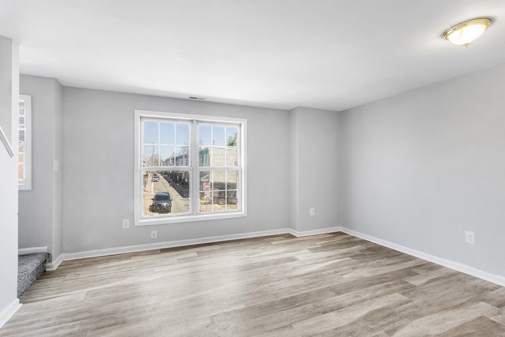an empty living room with a large window and wooden floors