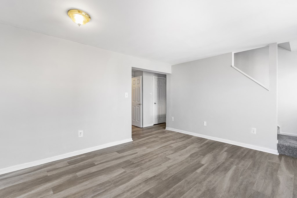 an empty living room with white walls and wood flooring