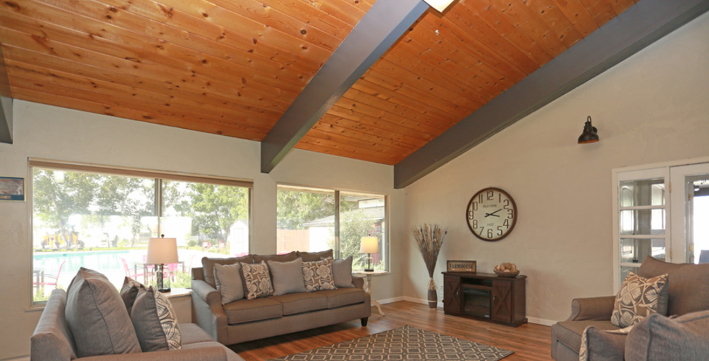 a living room with a wooden ceiling and a large window