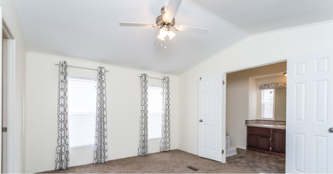 a living room with white walls and a ceiling fan