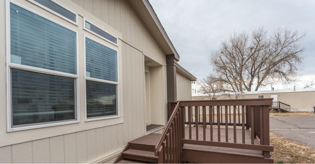 a home with a wooden deck and a tree in the background