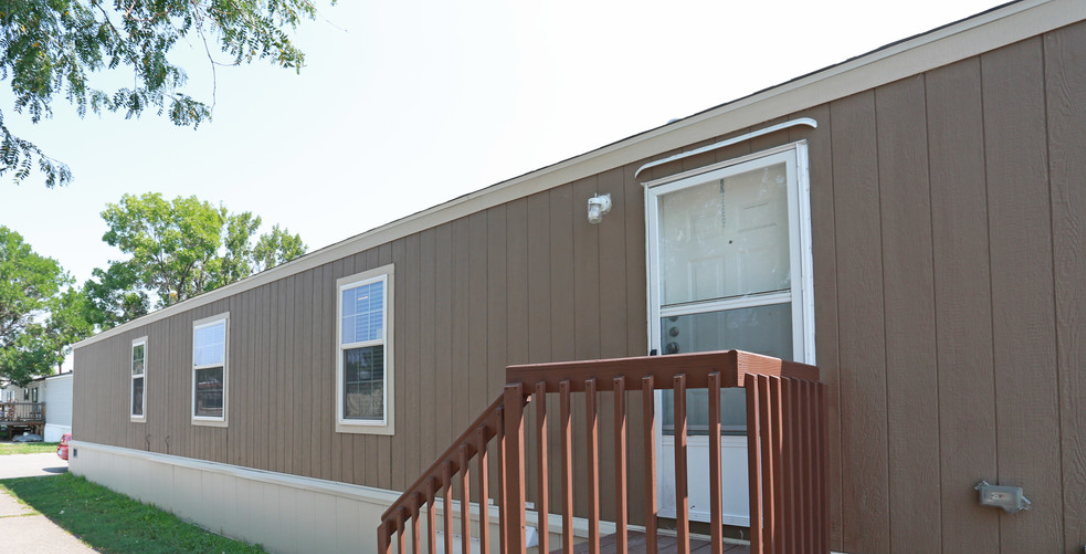 a brown and white mobile home with a wooden deck