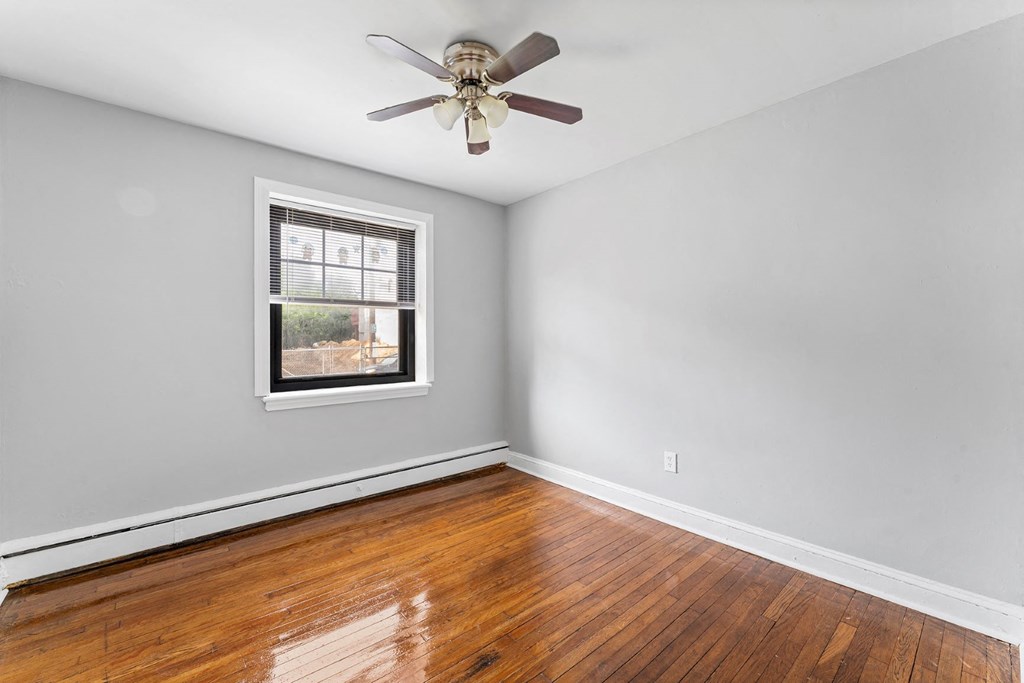 an empty bedroom with wood floors and a ceiling fan
