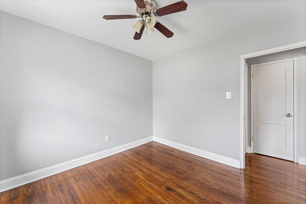 a empty room with wood floors and a ceiling fan