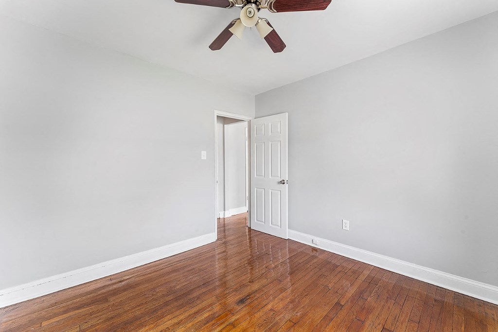 a empty room with wood floors and a ceiling fan