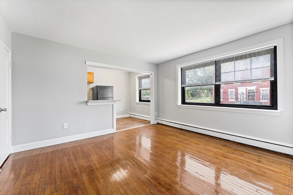 an empty living room with a large window and wooden floors