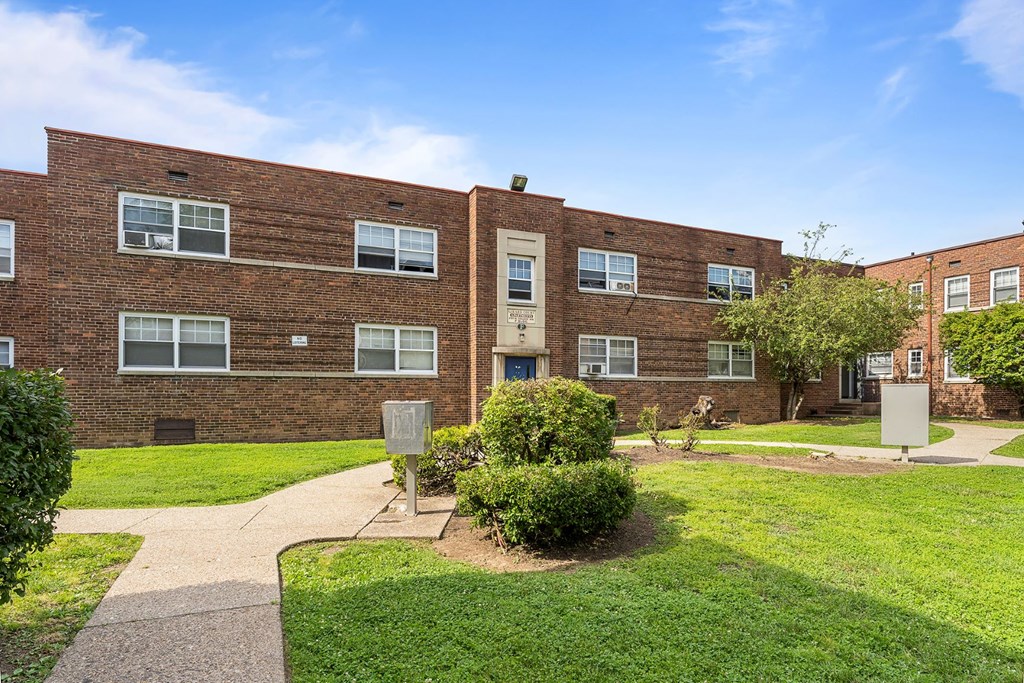 a brick building with a green lawn and sidewalk in front of it