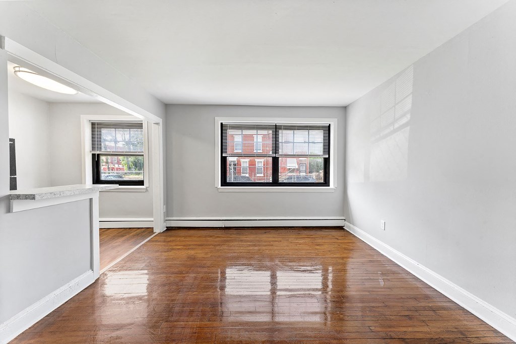 an empty living room with wood floors and a window
