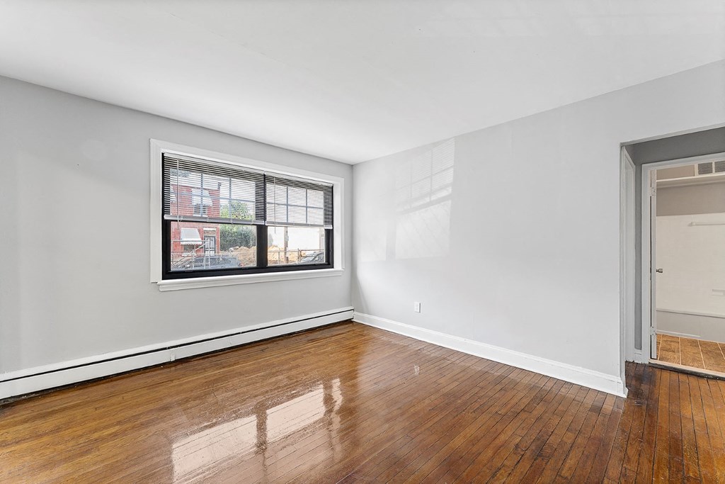 an empty room with wood floors and a window