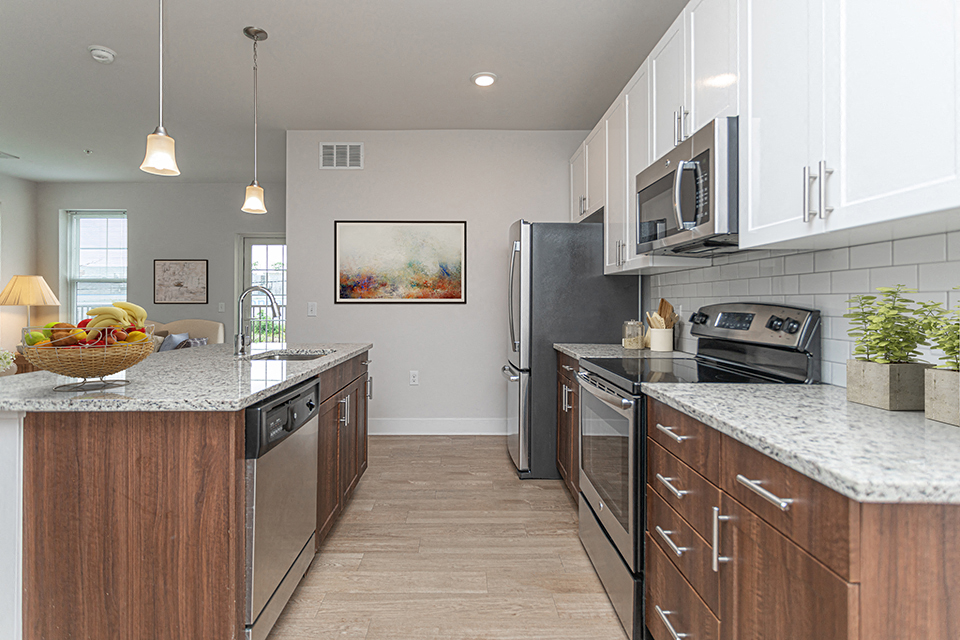 Galley kitchen with marbled countertops, hardwood flooring, and overhead lighting