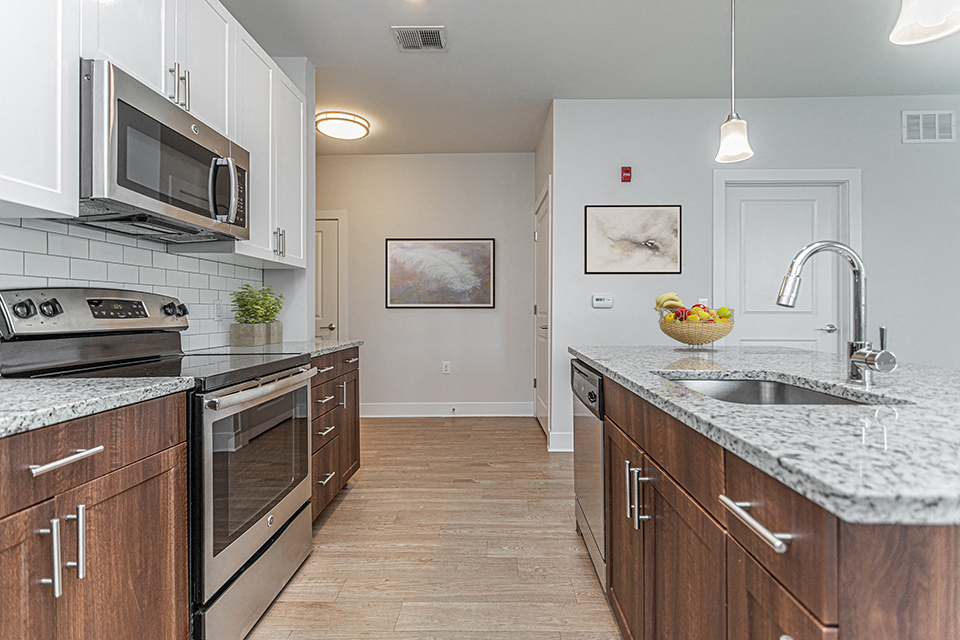 Modern galley kitchen with marbled countertops, stainless steel appliances, and hardwood flooring
