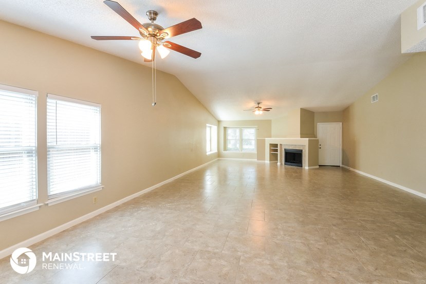 an empty living room with a ceiling fan and a fireplace