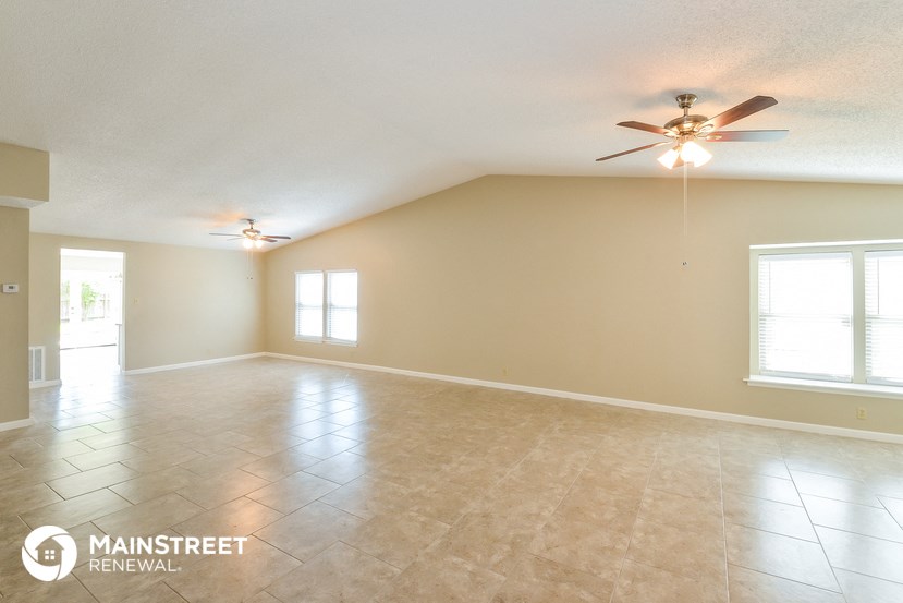 the spacious living room with tile flooring and a ceiling fan