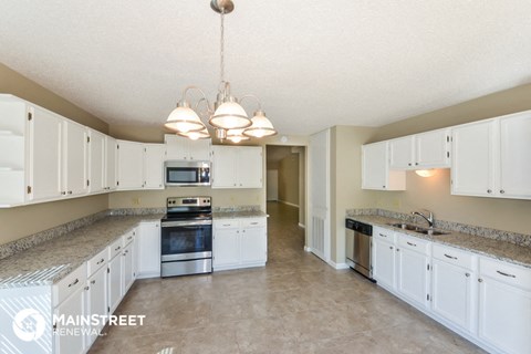 a large kitchen with white cabinets and stainless steel appliances
