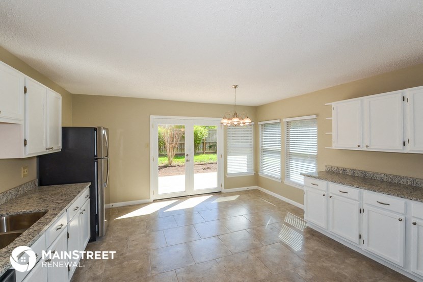 a kitchen with white cabinets and a black refrigerator