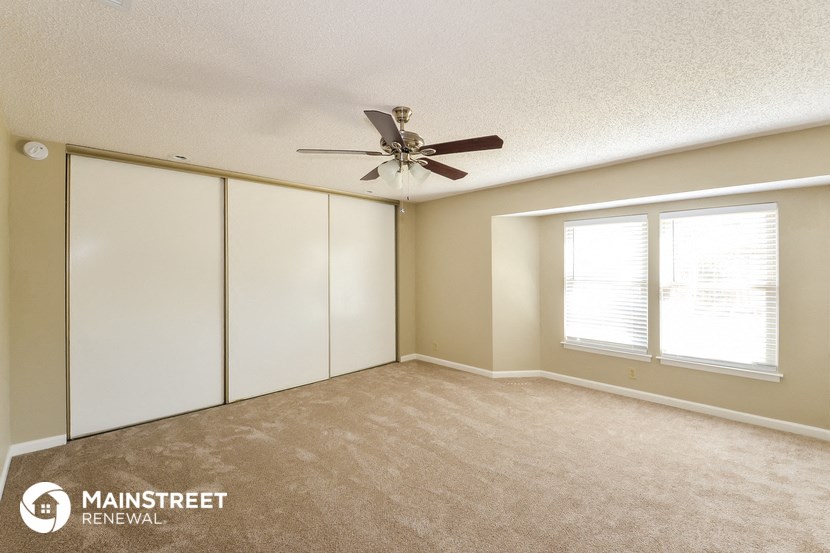 an empty room with a ceiling fan and two windows