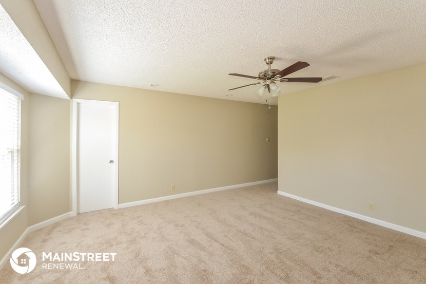 an empty living room with a ceiling fan