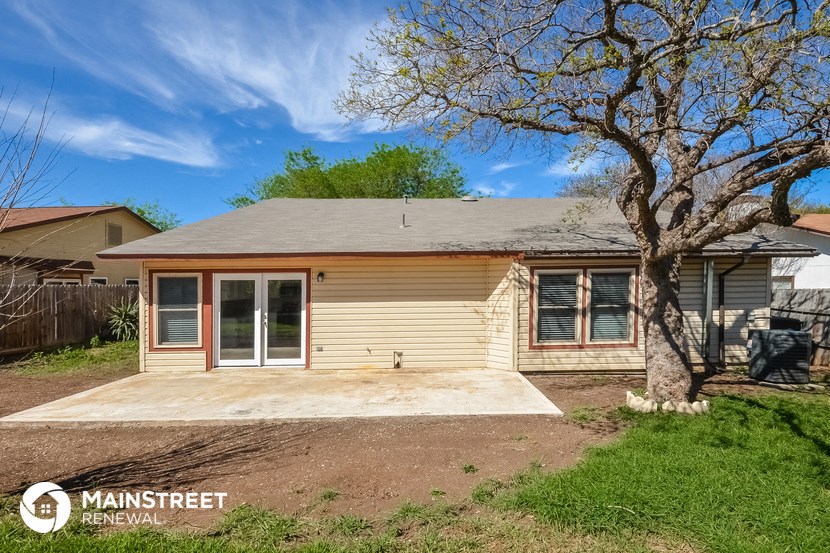 a small tan house with a porch and a tree