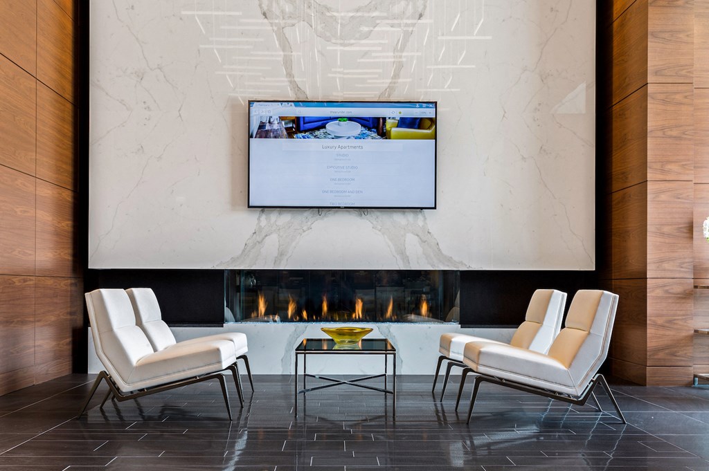 a living room with white chairs and a fireplace with a tv above it