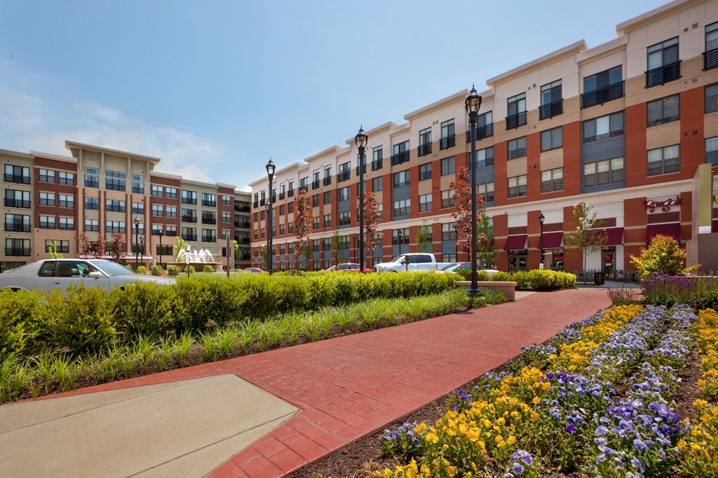 an exterior view of an apartment building with a sidewalk and flowers