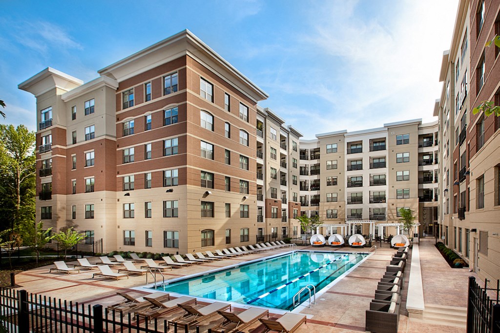 a swimming pool with lounge chairs in front of an apartment building