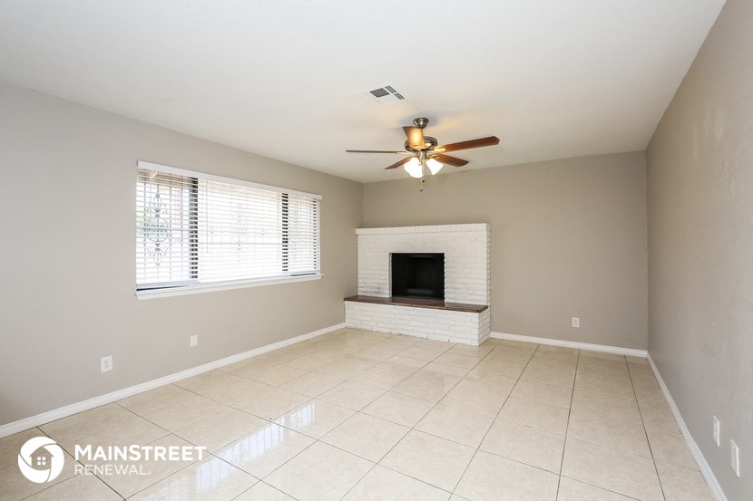 an empty living room with a fireplace and a ceiling fan