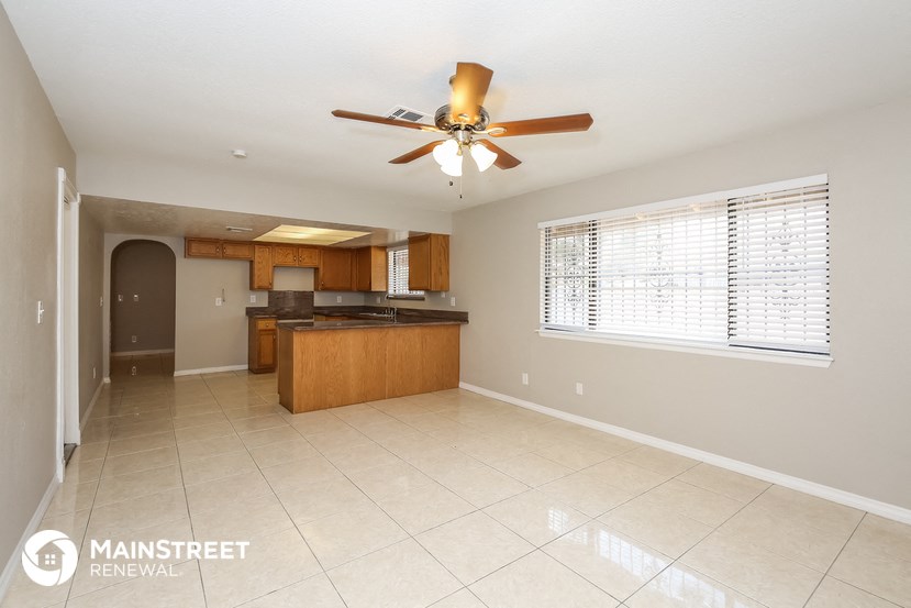an empty kitchen with a ceiling fan and a window