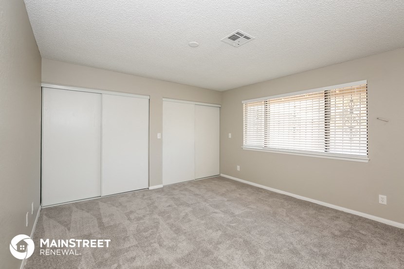 the living room of an apartment with carpet and a window
