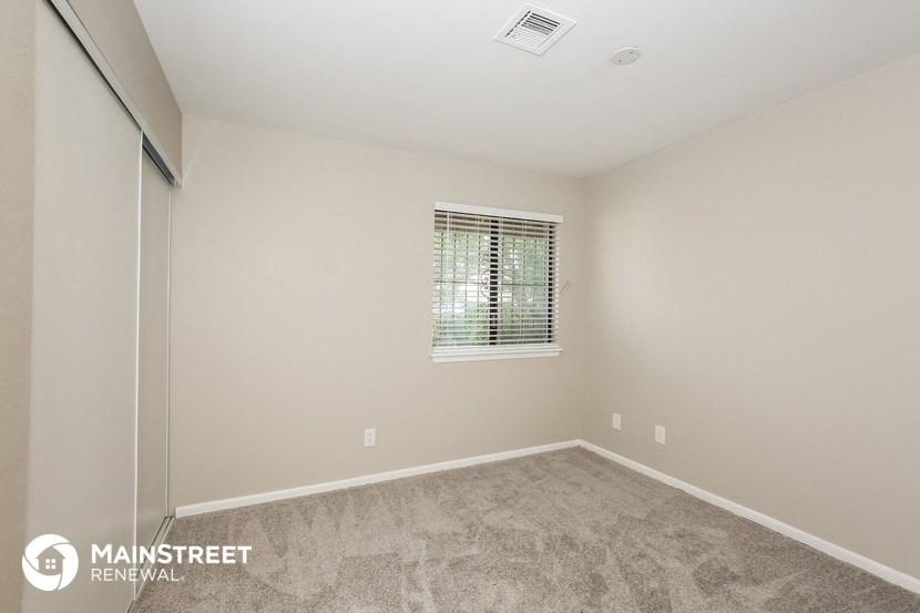 the master bedroom has a large window and carpeted flooring