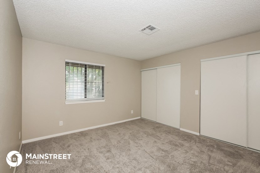 the spacious living room of a manufactured home with carpeted flooring and a window