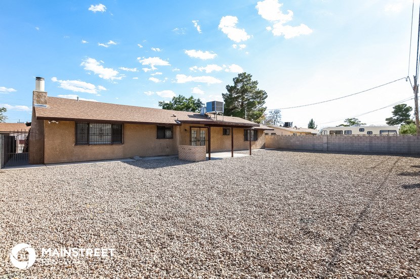 a small house with a gravel yard and a fence