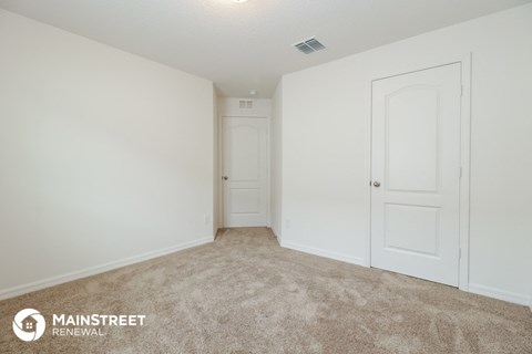 the spacious living room of an apartment with white doors and carpet