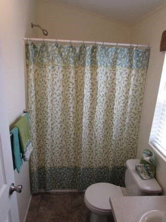 A bathroom with a toilet, shower curtain, and a towel hanging on the door.