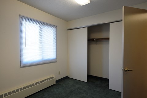 A room with a window, a door, and a closet.