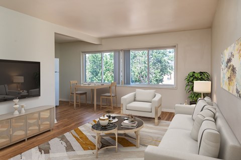 A living room with a white couch, a wooden coffee table, and a large window.