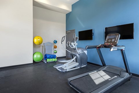 a gym with cardio equipment and a tv