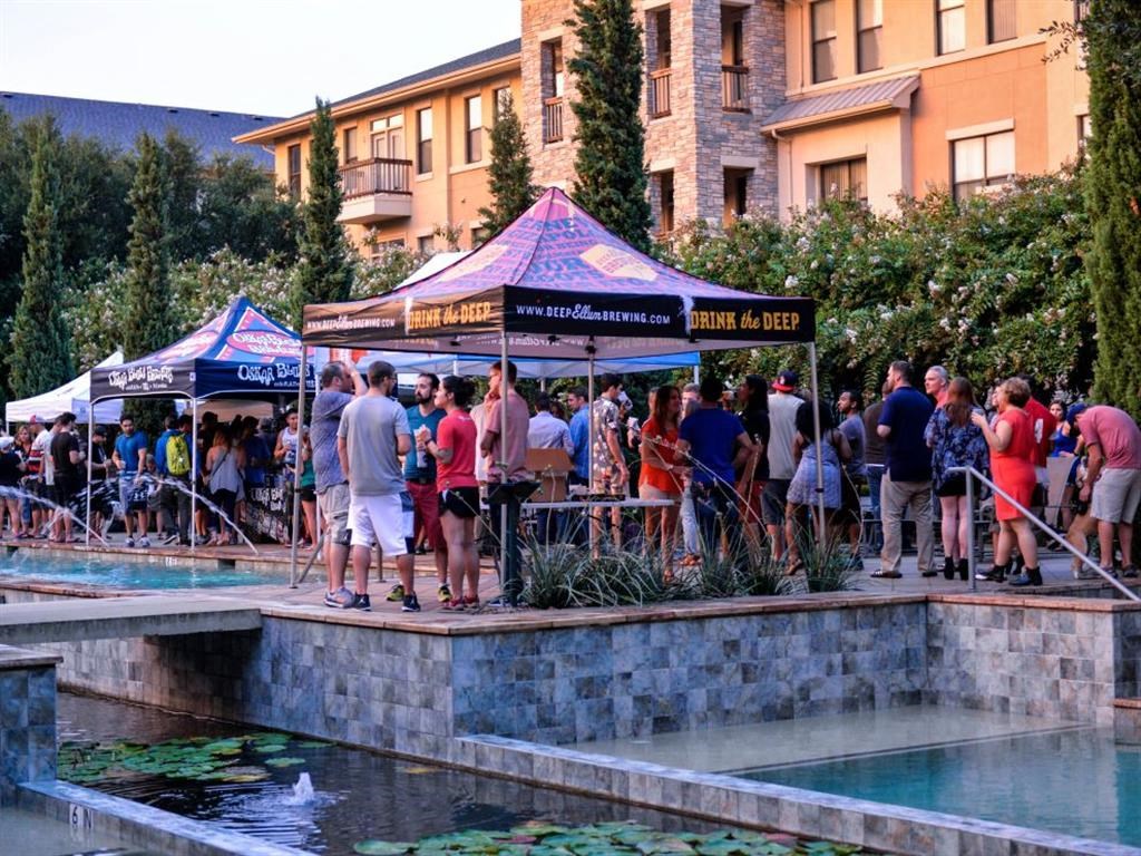 a crowd of people standing around a fountain and a tent
