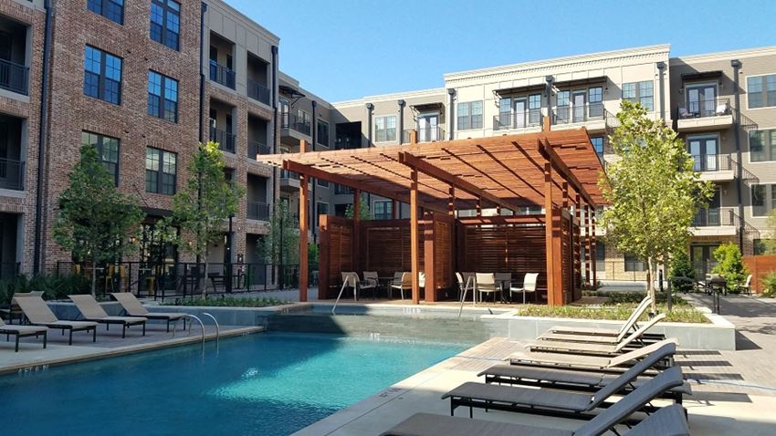 a pool with a wooden canopy next to an apartment building