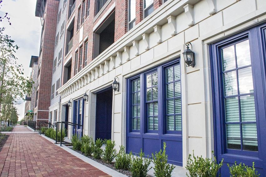 the exterior of a building with blue doors and a brick sidewalk
