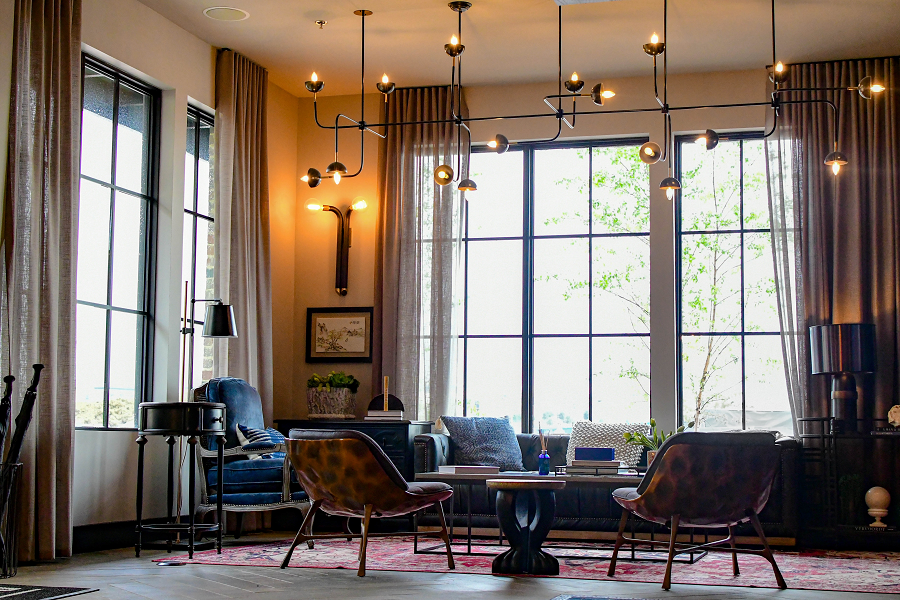 a living room with chairs and a table and large windows